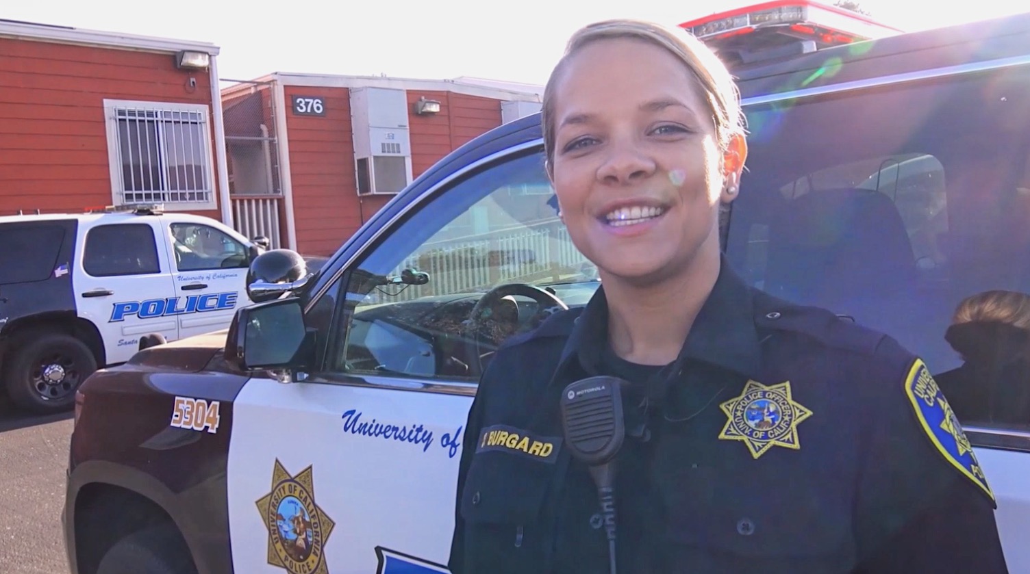 Officer Kiesow smiling in front of a UCPD patrol vehicle